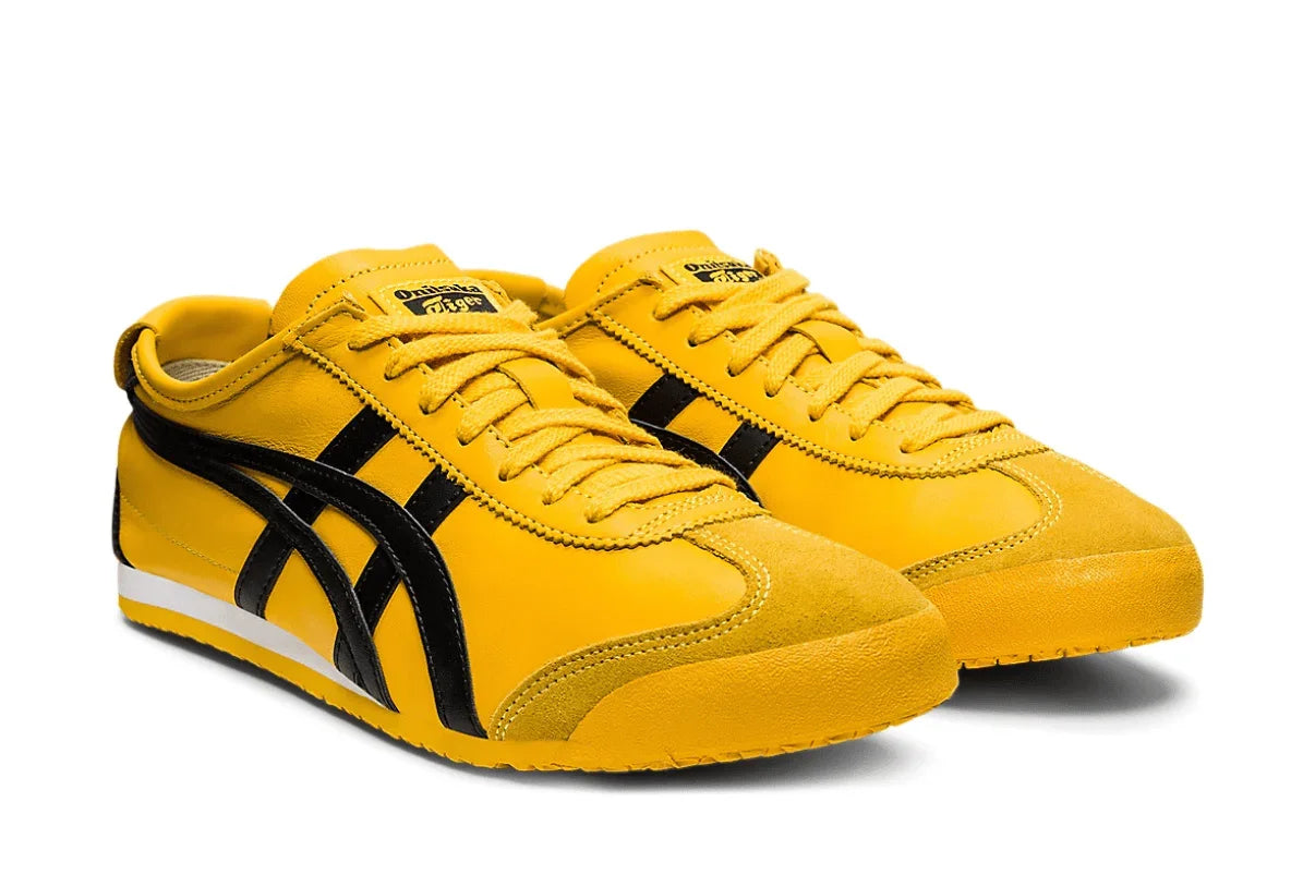 Tênis amarelo com detalhes pretos, design retrô, cabedal de couro e sola baixa.