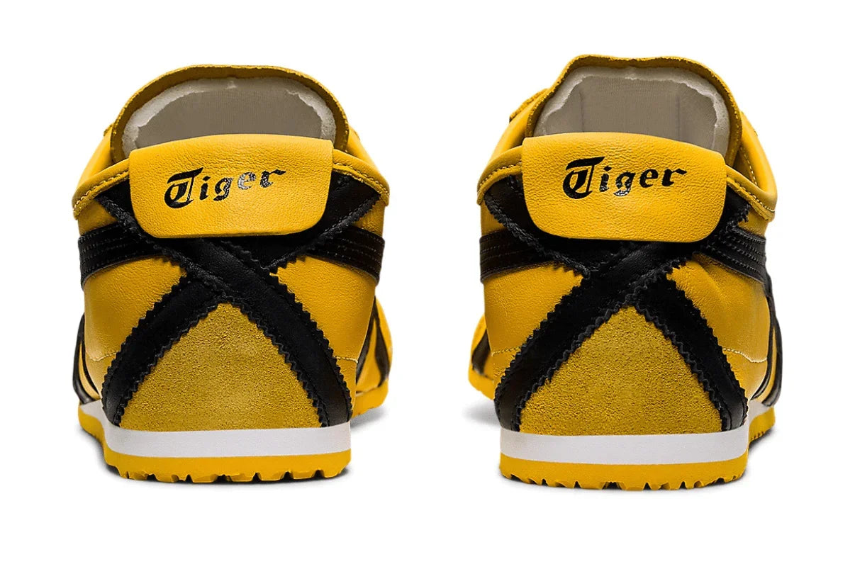 Tênis amarelo com detalhes pretos, visto de trás, solado baixo e logo Tiger no calcanhar.