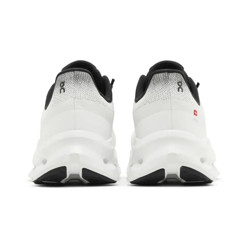 Tênis branco e preto visto de trás, sola robusta, design esportivo, ideal para corrida
