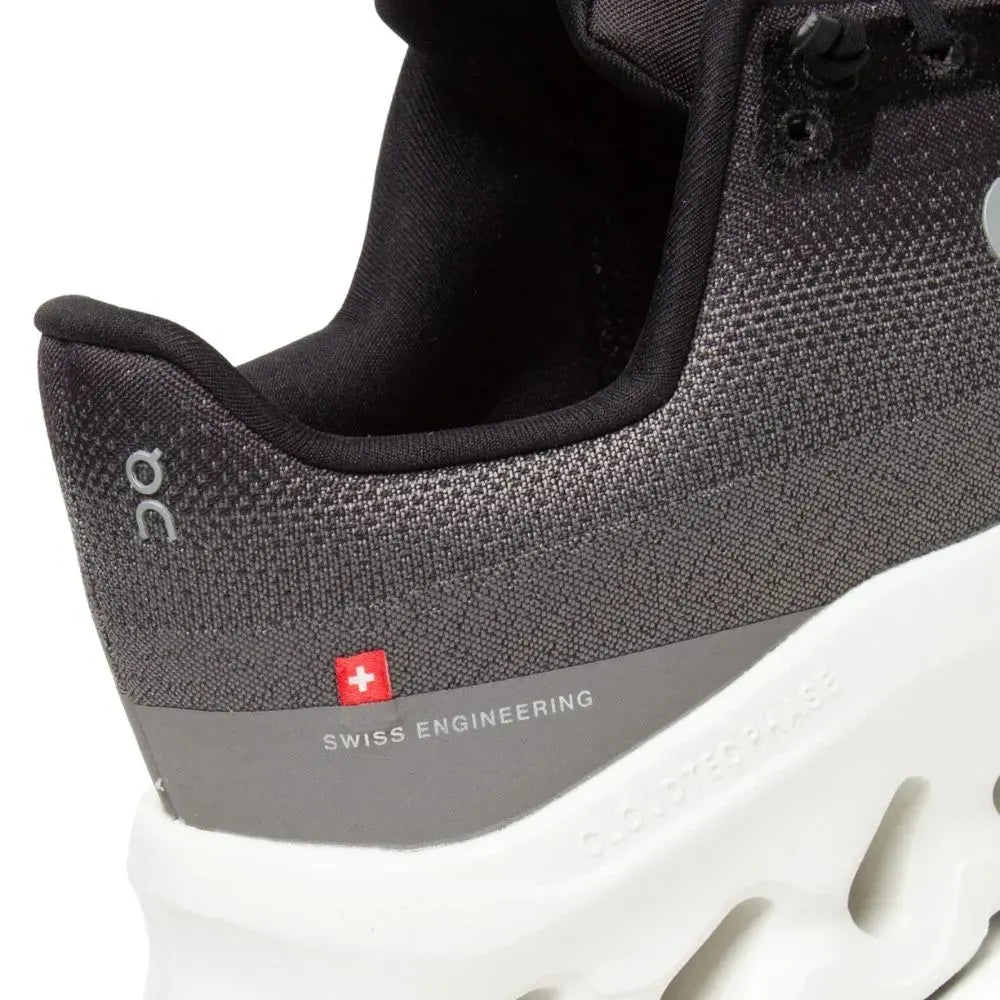 Detalhe de tênis preto On Running com solado branco e inscrição Swiss Engineering.