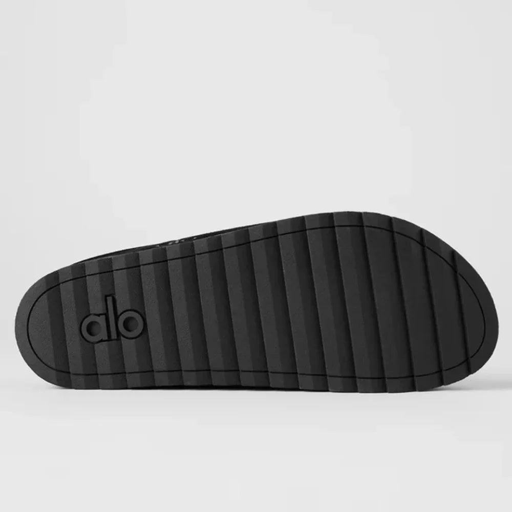 Solado de chinelo de recuperação preto com relevo texturizado e logo, em fundo claro