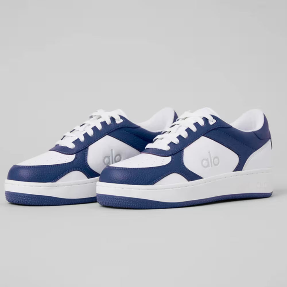 Tênis azul e branco de couro com logo alo, modelo esportivo, solado baixo, vista lateral.