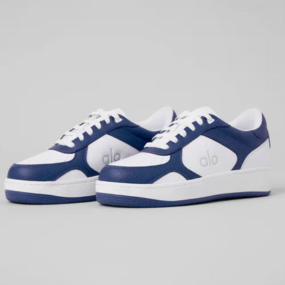 Tênis azul e branco de couro com logo alo, modelo esportivo, solado baixo, vista lateral.