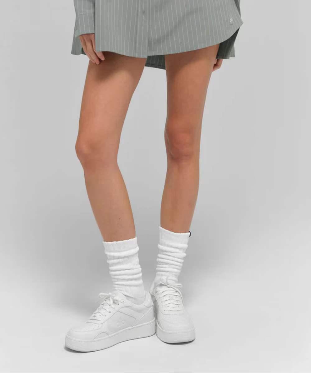 Tênis branco casual cano baixo estilo Alo Yoga Recovery Mode em modelo com meias brancas.