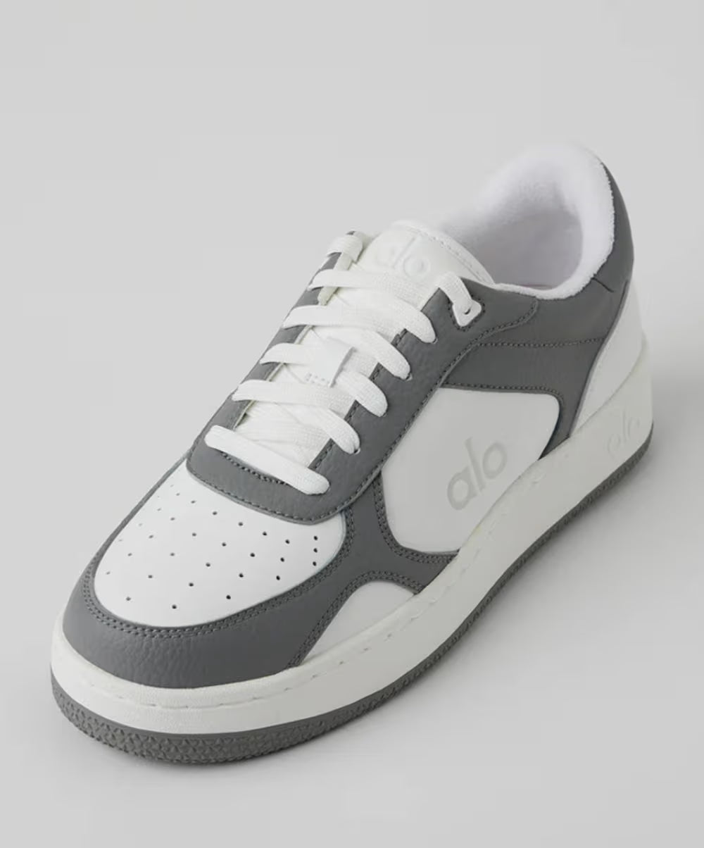 Tênis casual cinza e branco com cadarço, solado robusto e detalhes perfurados no cabedal.