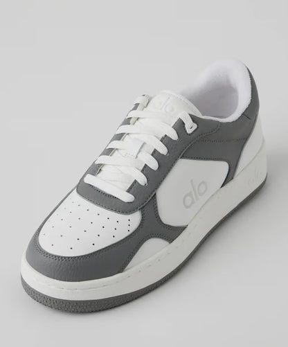 Tênis casual cinza e branco com cadarço, solado robusto e detalhes perfurados no cabedal.