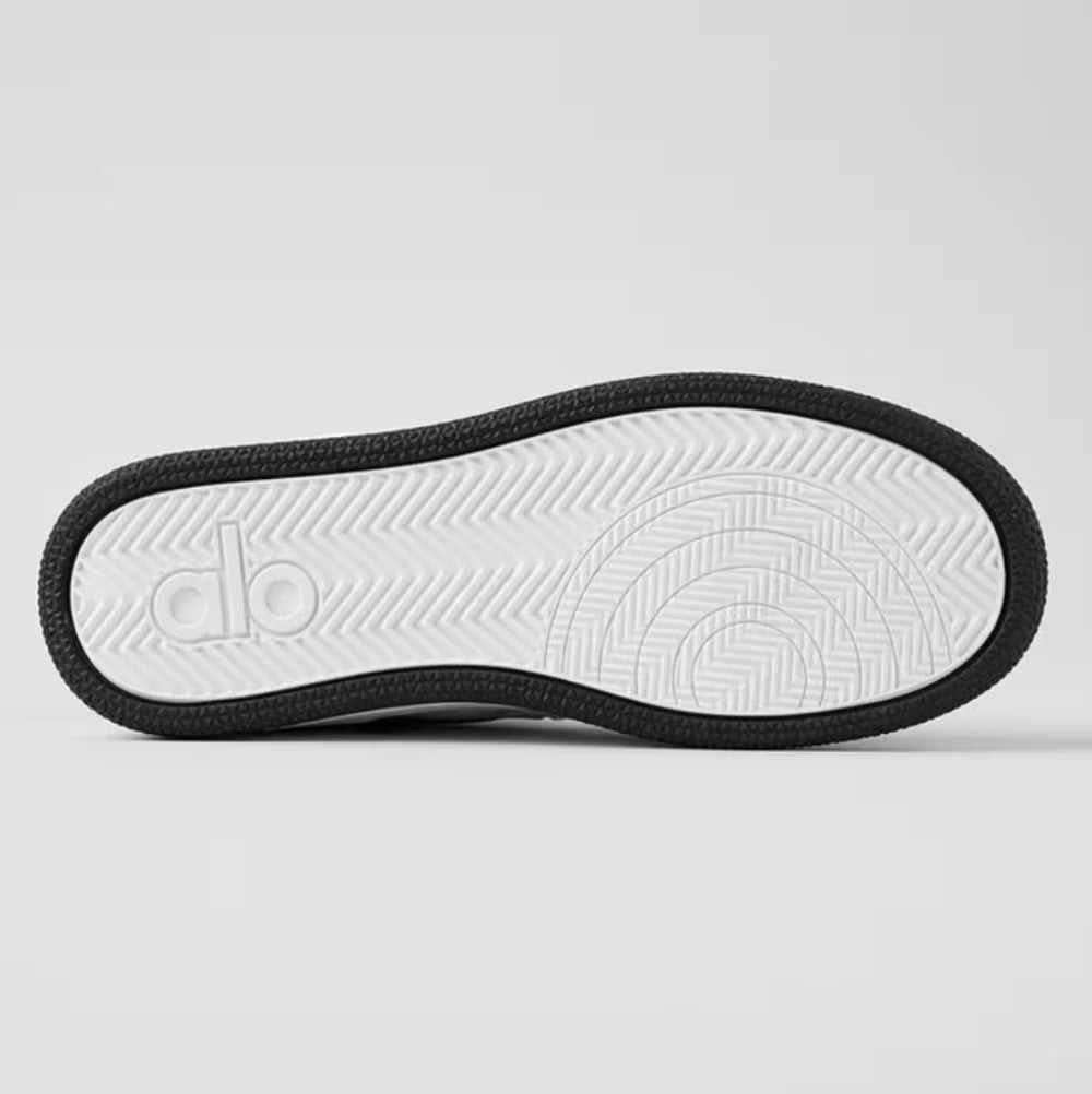 Solado de tênis esportivo preto e branco com textura antiderrapante e detalhes circulares.