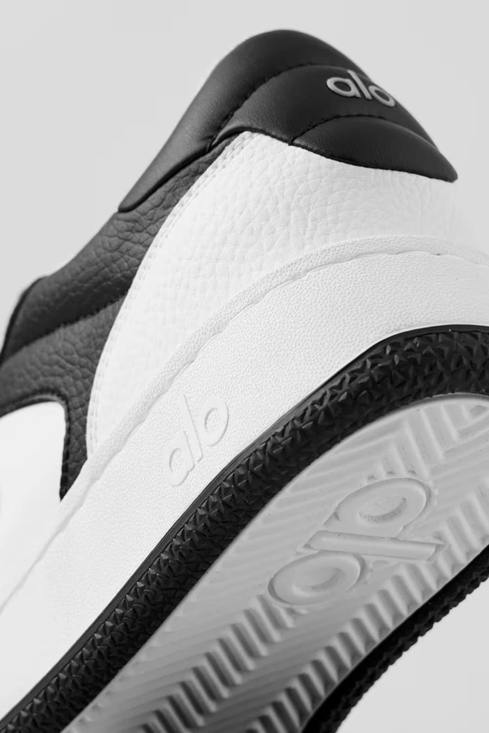 Detalhe do tênis preto e branco Alo Yoga, foco na parte traseira e sola em textura.
