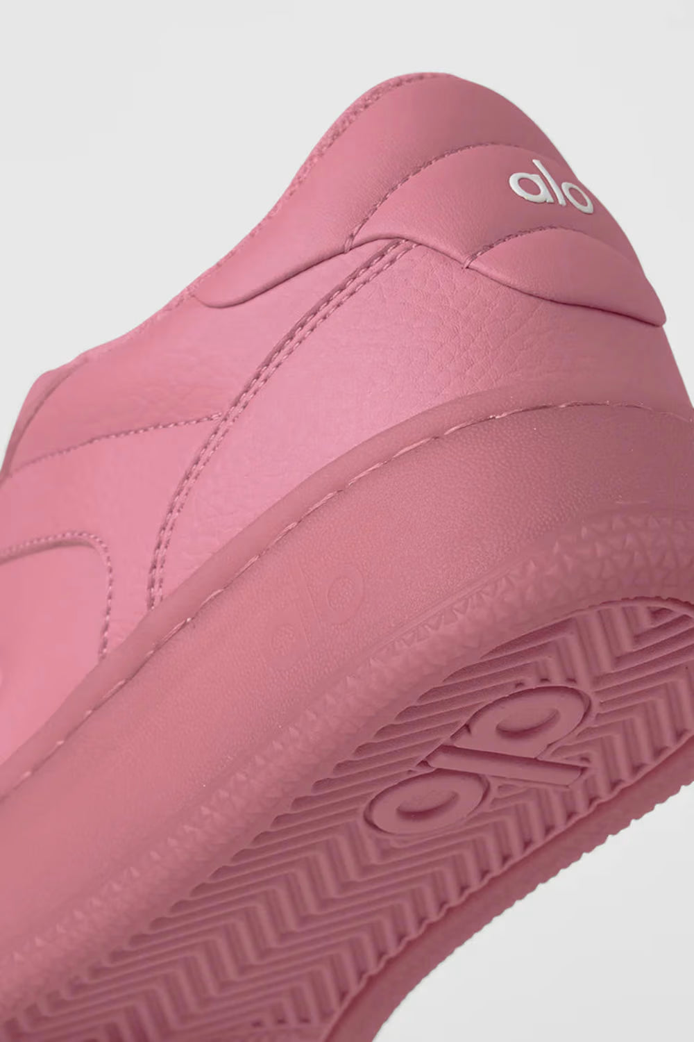 Detalhe de tênis esportivo rosa Alo Yoga com logo em relevo e solado texturizado