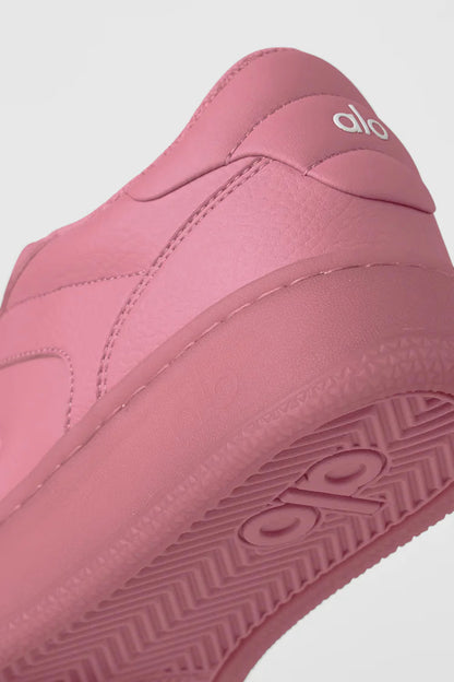 Detalhe de tênis esportivo rosa Alo Yoga com logo em relevo e solado texturizado