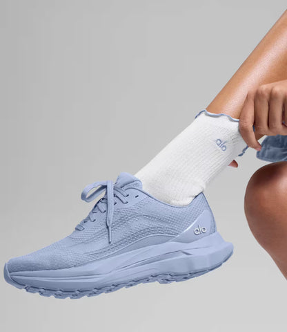 Tênis Alo Yoga Runner azul em modelo com vista lateral