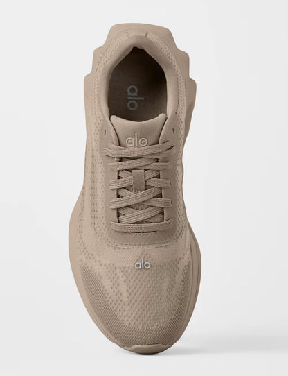 Tênis esportivo bege com cabedal knit, logo "alo", visualizado de cima, estilo casual moderno.