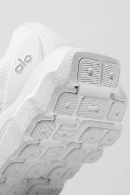Tênis esportivo branco com sola texturizada e detalhe lateral, ideal para corrida e treino.