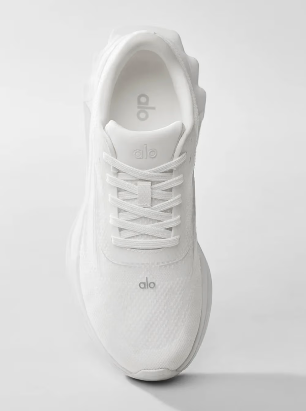 Tênis branco esportivo Alo Yoga visto de cima, com cadarço e design minimalista