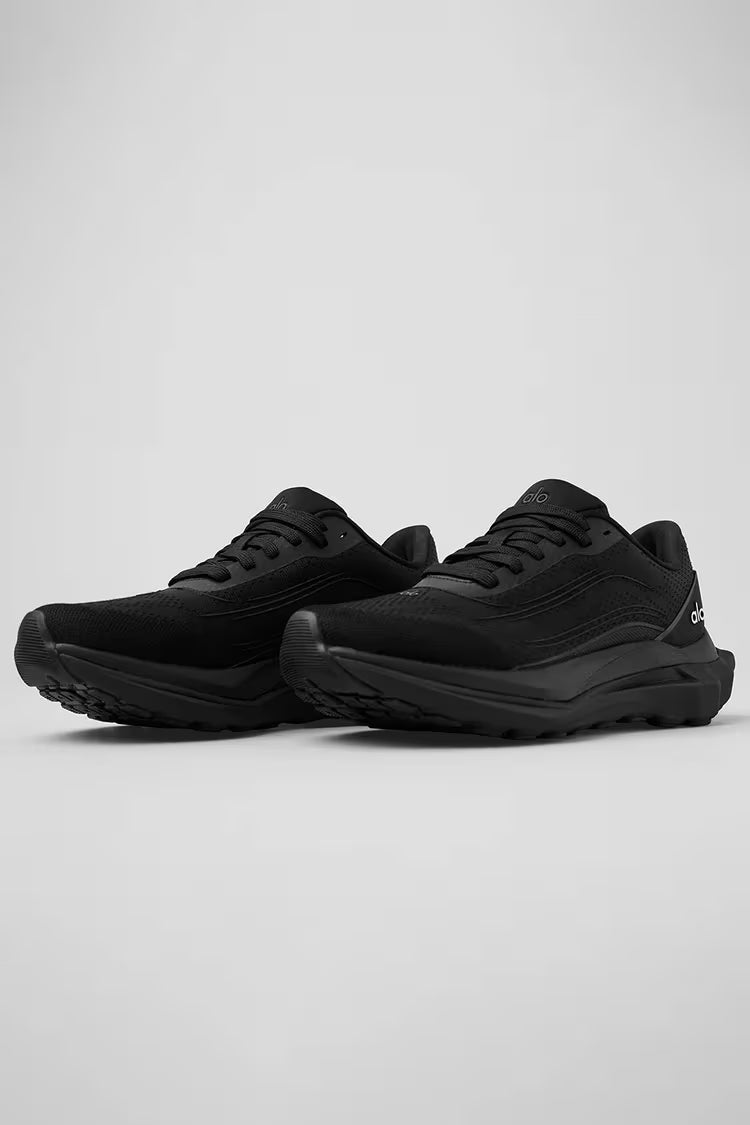 Tênis esportivo preto Alo Yoga para corrida, solado robusto e design moderno, vista lateral.