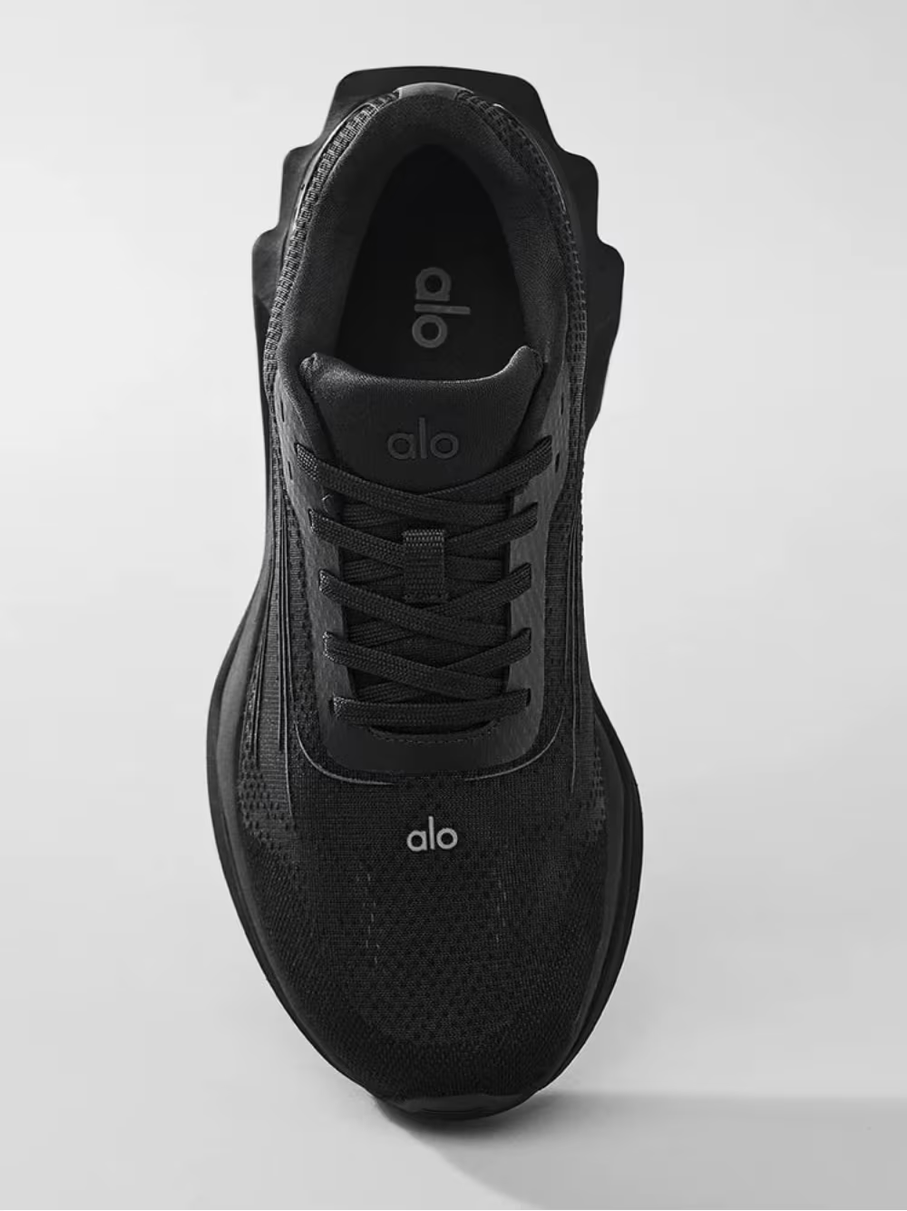 Tênis preto Alo Yoga visto de cima, design moderno, cabedal em malha e cadarço preto.