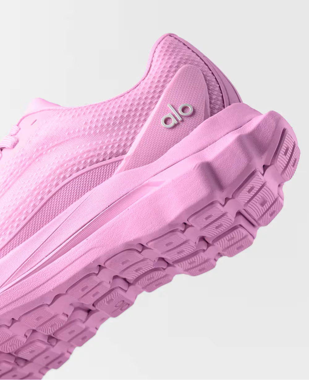 Tênis esportivo rosa com sola robusta e textura em tecido, detalhe de logo na lateral.