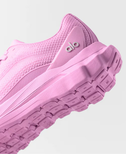 Tênis esportivo rosa com sola robusta e textura em tecido, detalhe de logo na lateral.