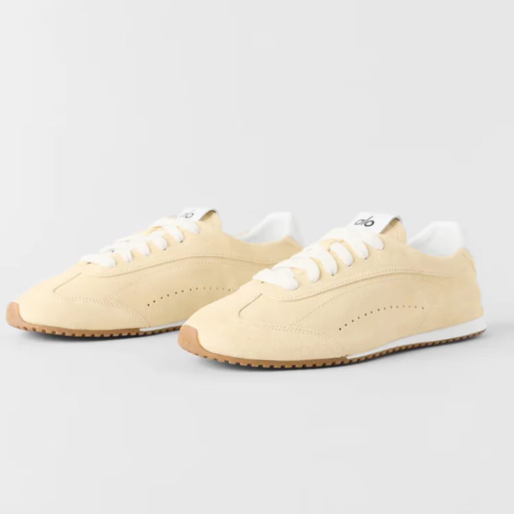 Tênis casual bege com detalhes dourados, solado de borracha e cadarço branco, estilo moderno.