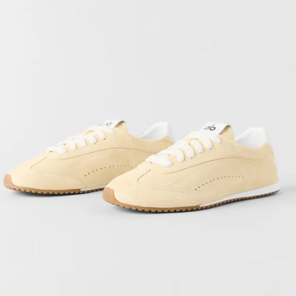 Tênis casual bege com detalhes dourados, solado de borracha e cadarço branco, estilo moderno.