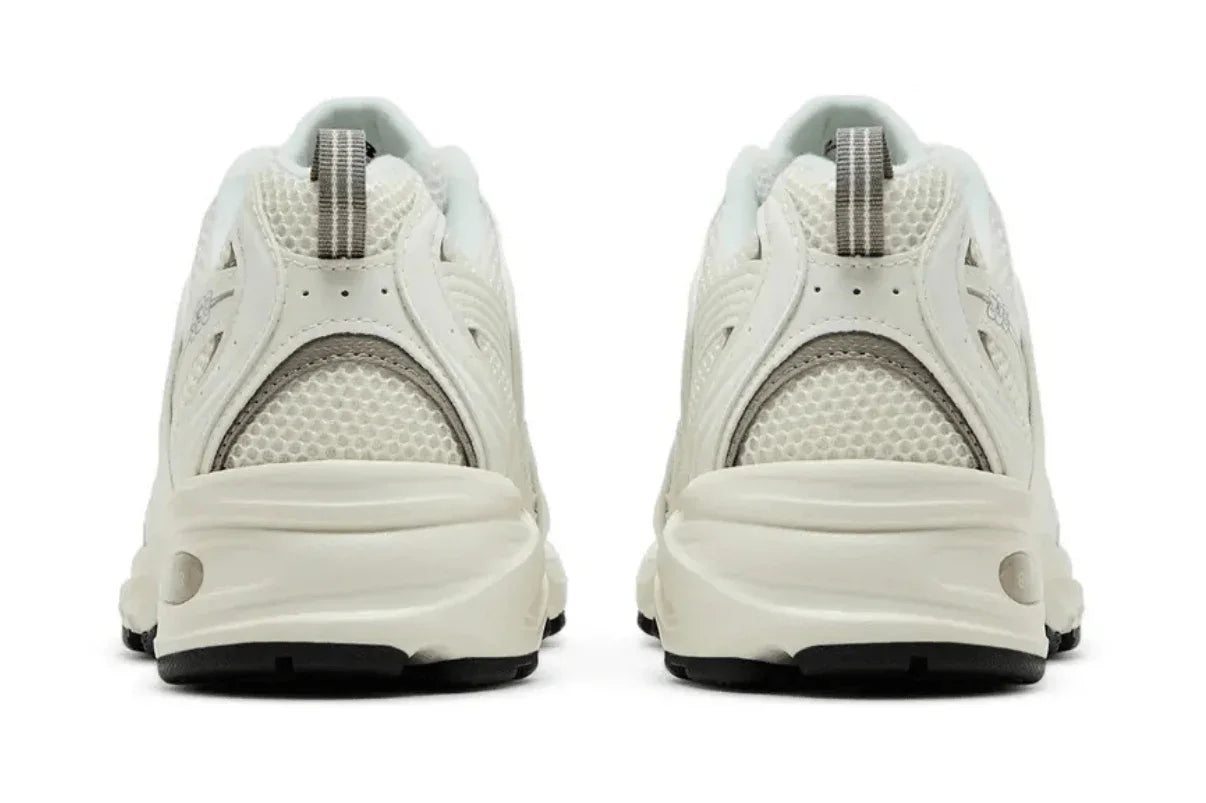 Tênis esportivo branco com detalhes cinza e sola robusta vistos de trás, tecido em mesh.