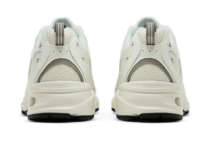 Tênis esportivo branco com detalhes cinza e sola robusta vistos de trás, tecido em mesh.