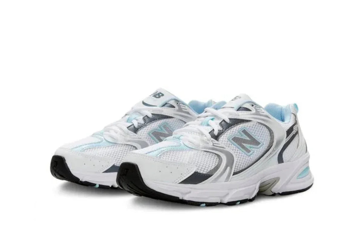 Tênis branco esportivo com detalhes cinza e azul, estilo sneaker moderno, fundo branco.