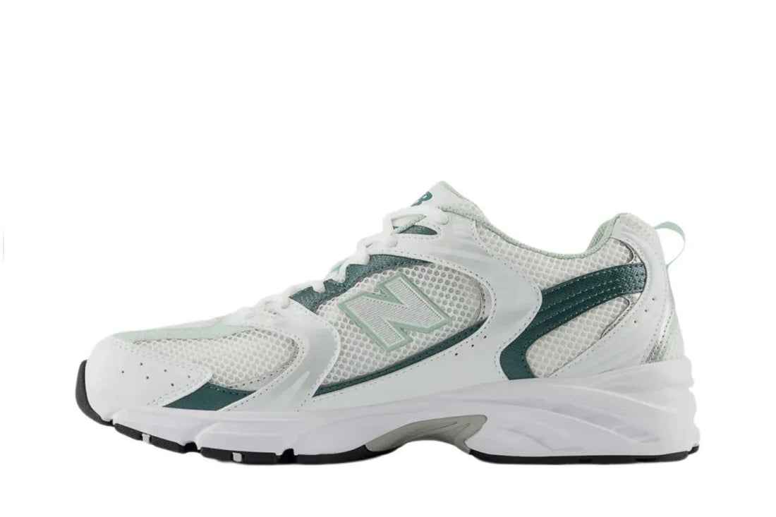 Tênis esportivo branco com detalhes verdes, solado robusto e design moderno, ideal para corrida.