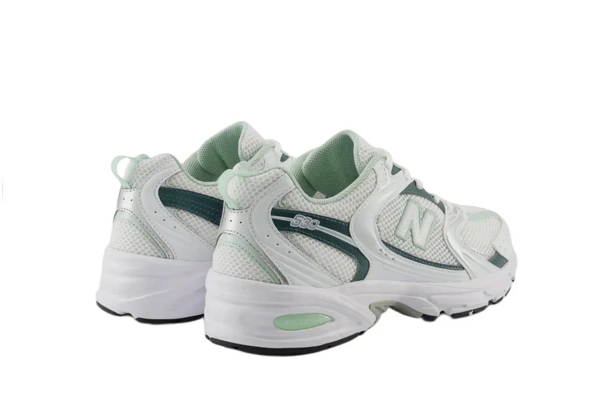 Tênis branco e verde claro modelo 530, com design esportivo e detalhes em mesh.