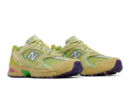 Tênis verde New Balance 530 com solado amarelo e detalhes roxos e verdes, estilo retrô.