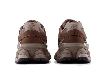 Tênis marrom New Balance 9060 visto de trás, solado robusto e detalhes em bege.