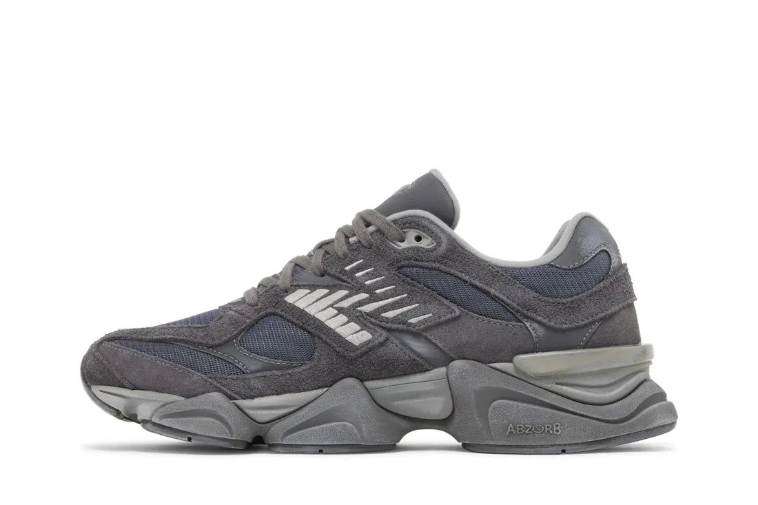 Tênis cinza esportivo New Balance 9060, com detalhes em camurça, mesh e solado robusto.