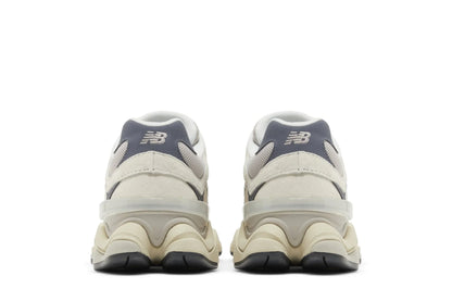 Tênis cinza New Balance 9060 visto de trás, solado robusto e detalhes em mesh.