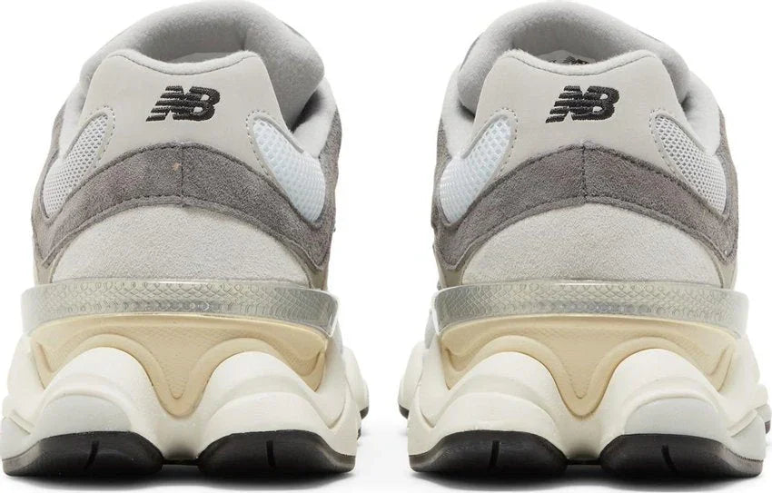 Tênis cinza com detalhes bege e branco, solado robusto, vista traseira, modelo esportivo.