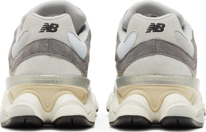 Tênis cinza com detalhes bege e branco, solado robusto, vista traseira, modelo esportivo.
