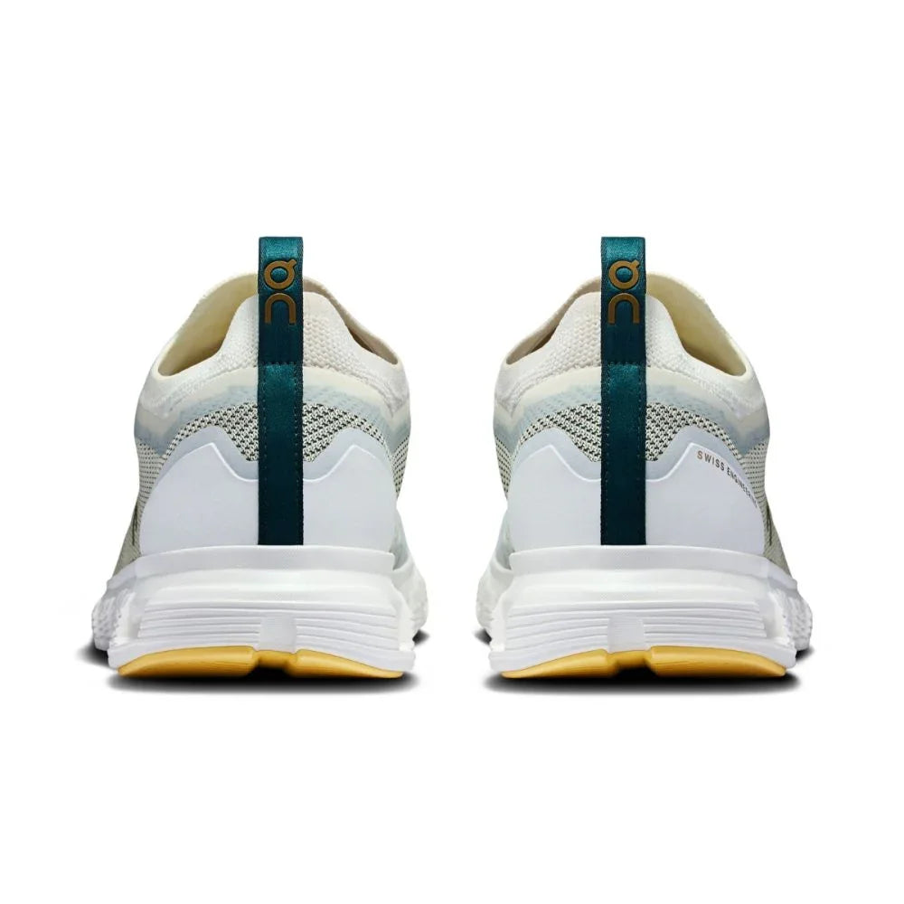 Tênis esportivo branco On Running Cloud 6 Versa visto de trás, detalhes verdes e sola amarela.