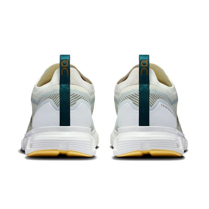 Tênis esportivo branco On Running Cloud 6 Versa visto de trás, detalhes verdes e sola amarela.