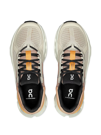 Tênis esportivo bege com detalhes laranja e preta, visto de cima, modelo Cloudrunner 2.