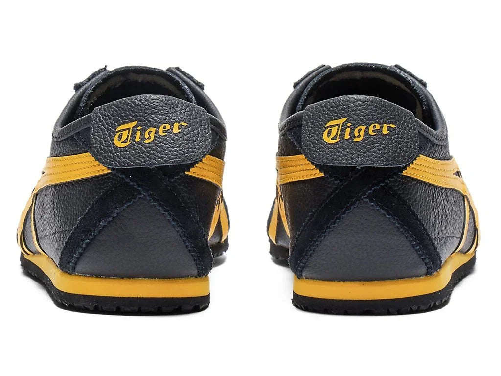 Tênis preto com detalhes amarelos, vistos de trás, com inscrição Tiger no calcanhar.