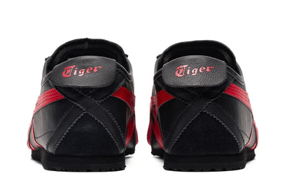 Tênis preto com detalhes vermelhos visto de trás, solado baixo e logo Tiger no calcanhar.