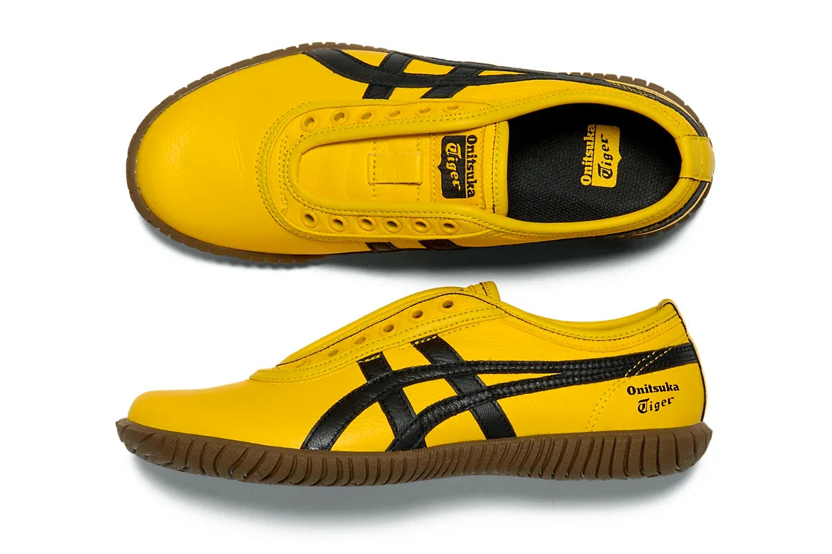 Tênis slip-on amarelo com detalhes pretos, solado marrom e logo lateral, estilo esportivo.