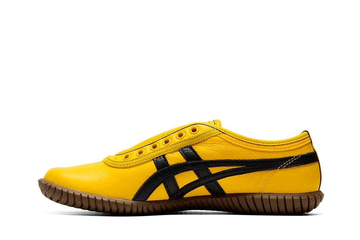Tênis slip on amarelo com detalhes pretos e solado de borracha marrom, estilo casual.