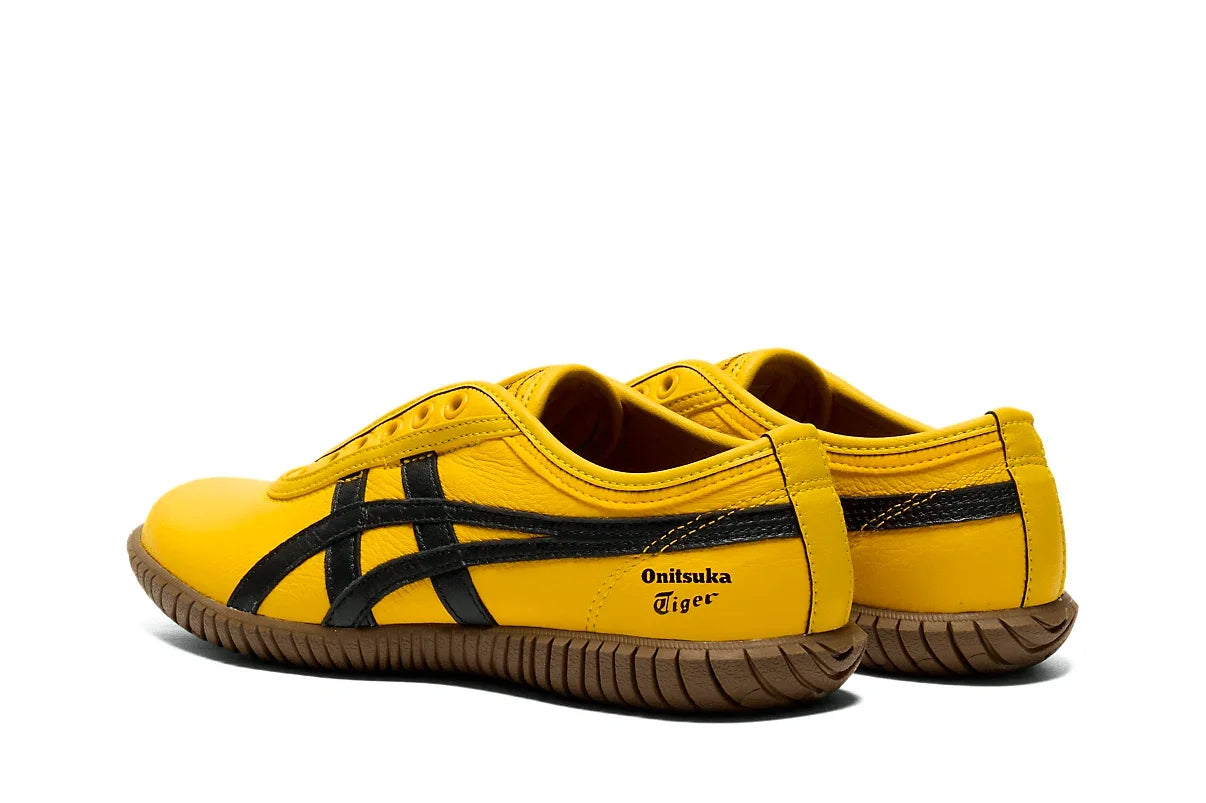 Tênis slip on amarelo com detalhes pretos e sola marrom, visual esportivo e moderno.